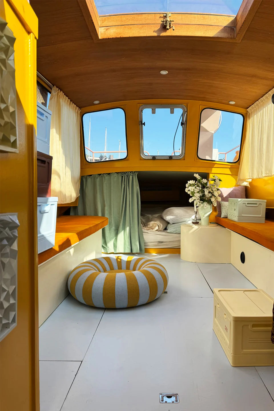 Bateau aménagé avec la collection Studio About. Des poufs et des caisses de rangement pour optimiser l'espace.