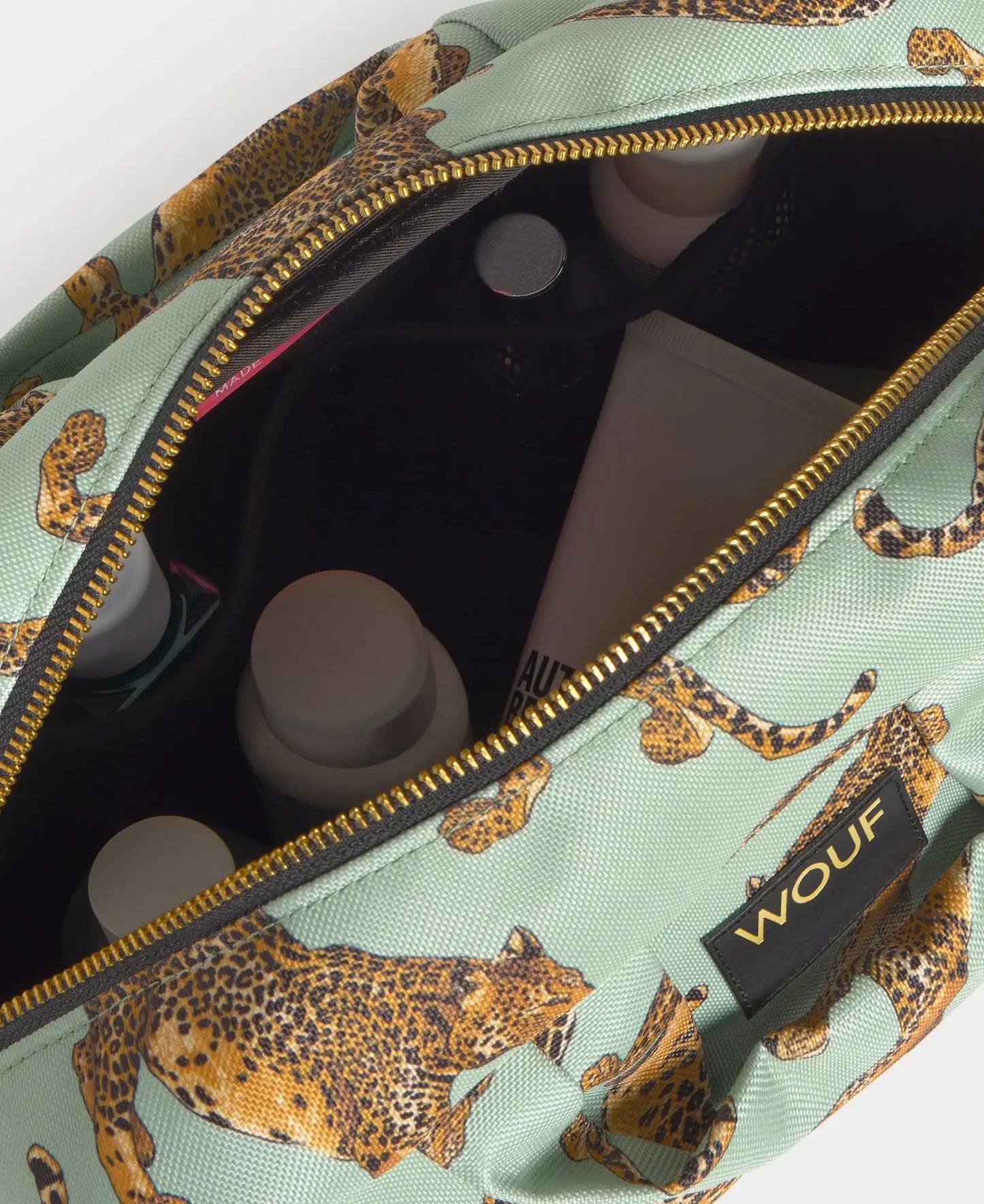 Grande trousse de toilette Emerald Leopard de chez Wouf ouverte avec des produits de beauté