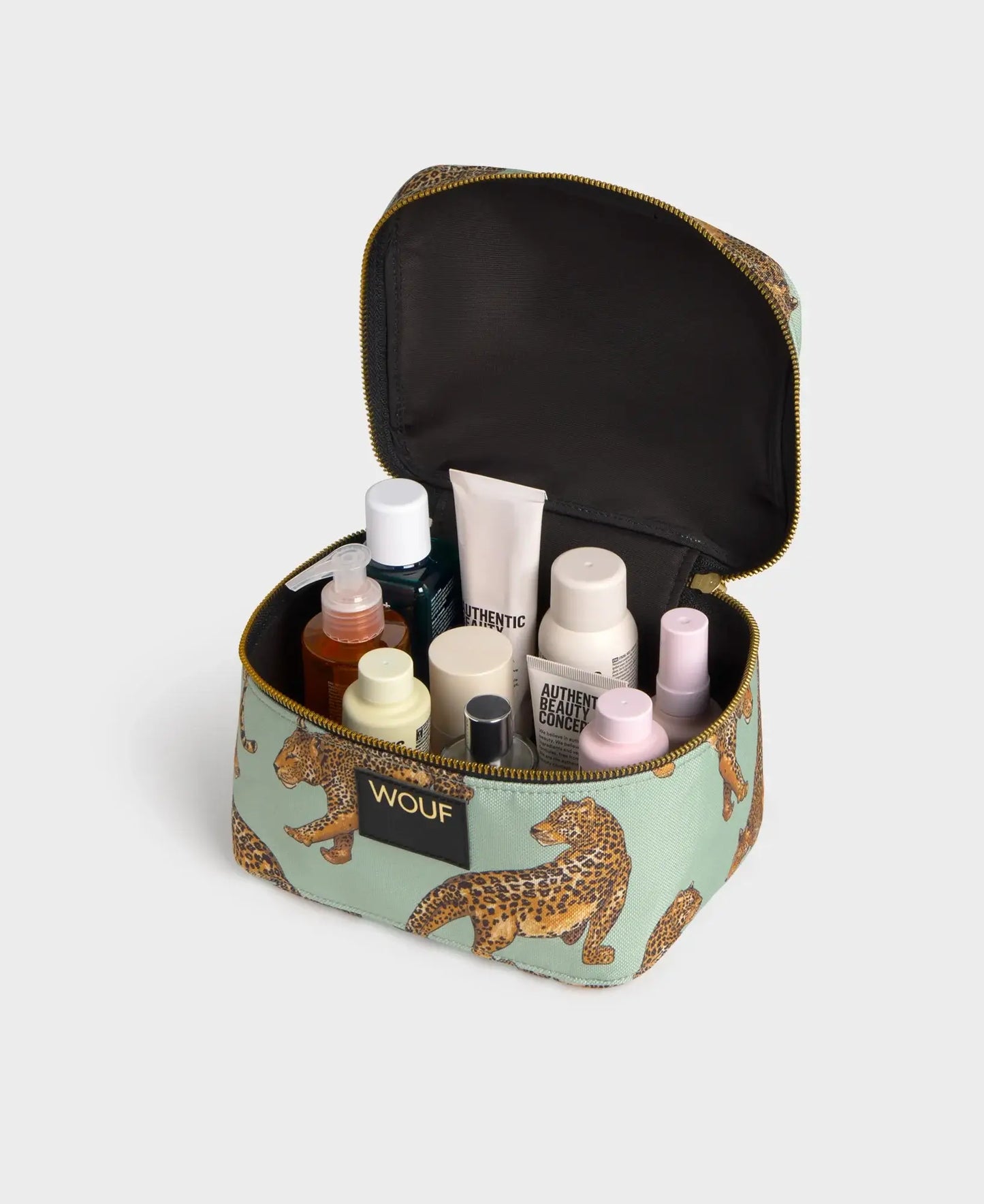 Trousse de toilette vanity Emerald Leopard de chez Wouf ouverte avec des produits de beauté et du maquillage